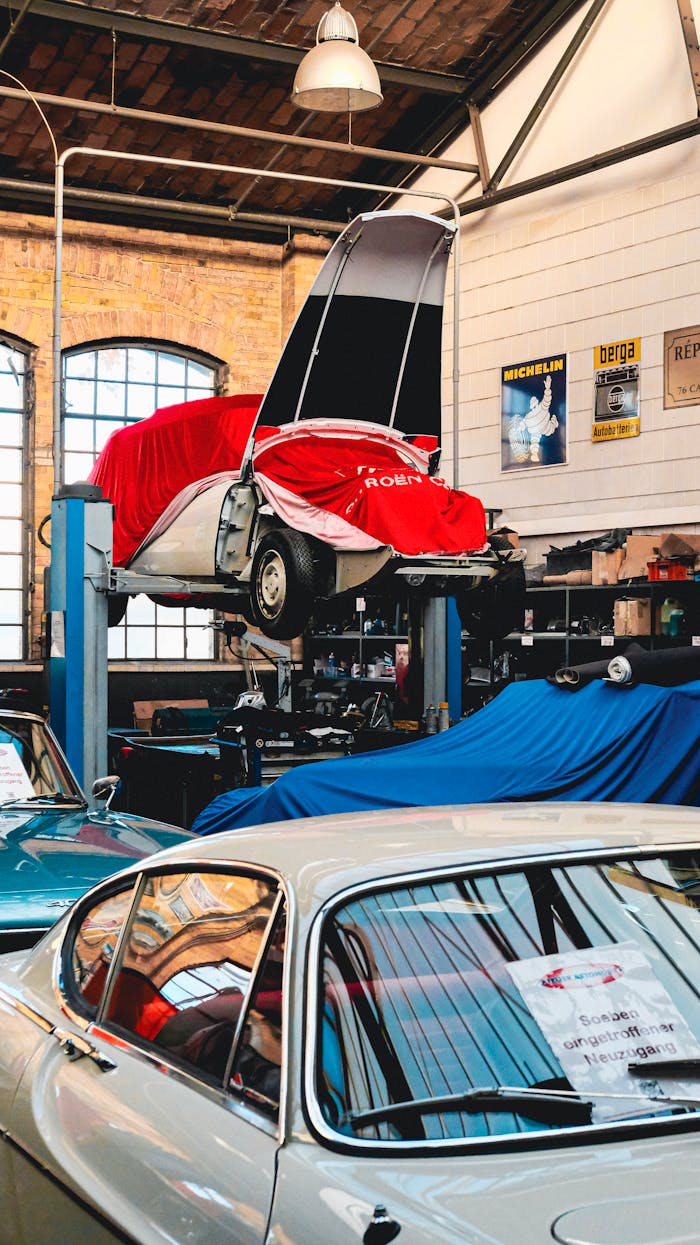 The Art of Drawing Readers In: Your attractive post title goes here A vintage car workshop featuring classic cars on lifts, covered and maintained indoors.