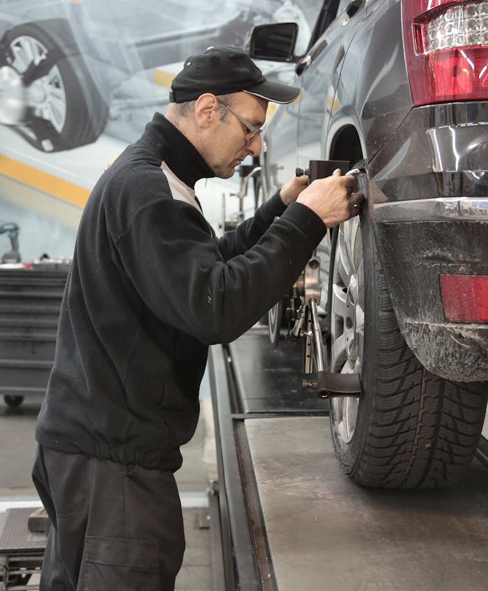 Crafting Captivating Headlines: Your awesome post title goes here Side view of a mechanic aligning a car tire in a professional auto workshop.